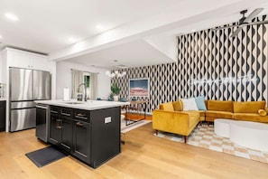 A modern kitchen with stainless steel appliances, a dining area with a yellow sofa, and a patterned wall. - Pool, Firepit, Mins to DT, SXSW, ACL, Sleeps 6 (Austin)