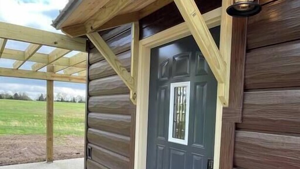 Ein Holzhaus mit einer dunklen Tür und einem Hauseingangsbereich.