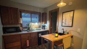Une cuisine avec des meubles en bois, un four à micro-ondes, un  évier et une carte accrochée au mur.