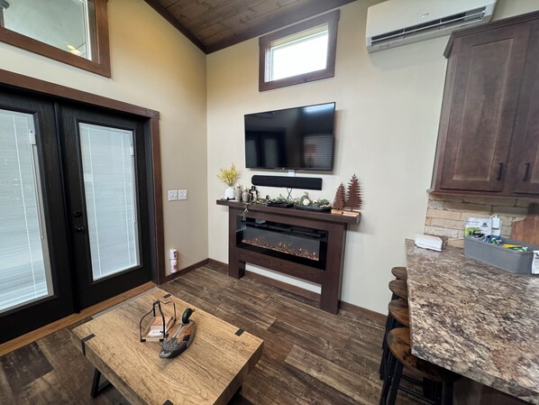 Una cocina moderna con televisor integrado, armarios de madera y encimera de granito.