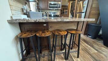 Una cocina con encimera de granito, electrodomésticos de acero inoxidable y taburetes de madera.