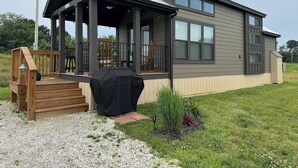 Uma casa moderna térrea com varanda coberta, um pequeno deck e gramado bem cuidado.