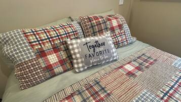 A bed with plaid bedding and a pillow with the text "Together is our favorite place to be."