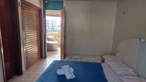 A hotel room with a bed, a small bedside table, and a view of a balcony. - Cumbuco - Beach house with pool and deck Ceará (Praia de Cumbuco Caucaia)
