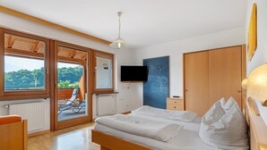 A bedroom with a bed, a television, a wardrobe, and a view through a sliding door.