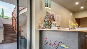 A reception desk with a sign reading 'Seaberhof,' a staircase, and a view of the outdoors. - Room 'Seaberhof 6' with Lake View, Shared Pool and Wi-Fi (Caldaro)