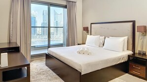 Une chambre d’hôtel moderne, dotée d’un grand lit, d’un bureau et offrant une vue sur le paysage urbain par la fenêtre.