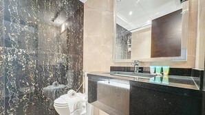 Une salle de bain moderne avec un mur en marbre, un plan de toilette noir et un grand miroir au-dessus du lavabo.