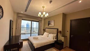 Une chambre d’hôtel moderne dotée d’un grand lit, d’un bureau et offrant une vue sur les toits de la ville depuis le balcon.