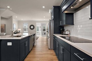 A modern kitchen with dark cabinetry, white countertops, and a central island. - Tide & Seek at Lighthouse Bay! (Ocean City)