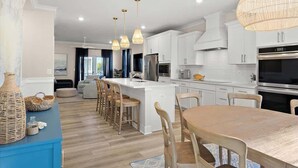 A modern kitchen with white cabinets, a large island, and pendant lighting.