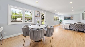 A spacious room with a dining table, chairs, and a sofa. - Coastal Modern Retreat | Large Group Getaway on 2 Acres (Arnold)