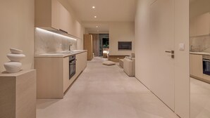 Eine moderne Küche mit einer zentralen Kochinsel, einem Essbereich mit einer Couch und einem an der Wand montierten Fernseher.