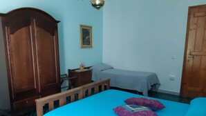 Une chambre à coucher comprenant un lit, une armoire en bois, une table de chevet et une petite table.