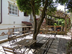 Un patio con mobiliario exterior, un árbol y una escalera.
