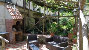 Une terrasse extérieure avec des meubles en osier, un four en briques et des plantes en pot.