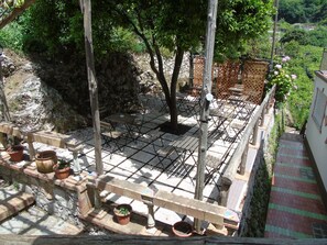 Un patio con mobiliario exterior, una pared de piedra y plantas en macetas.