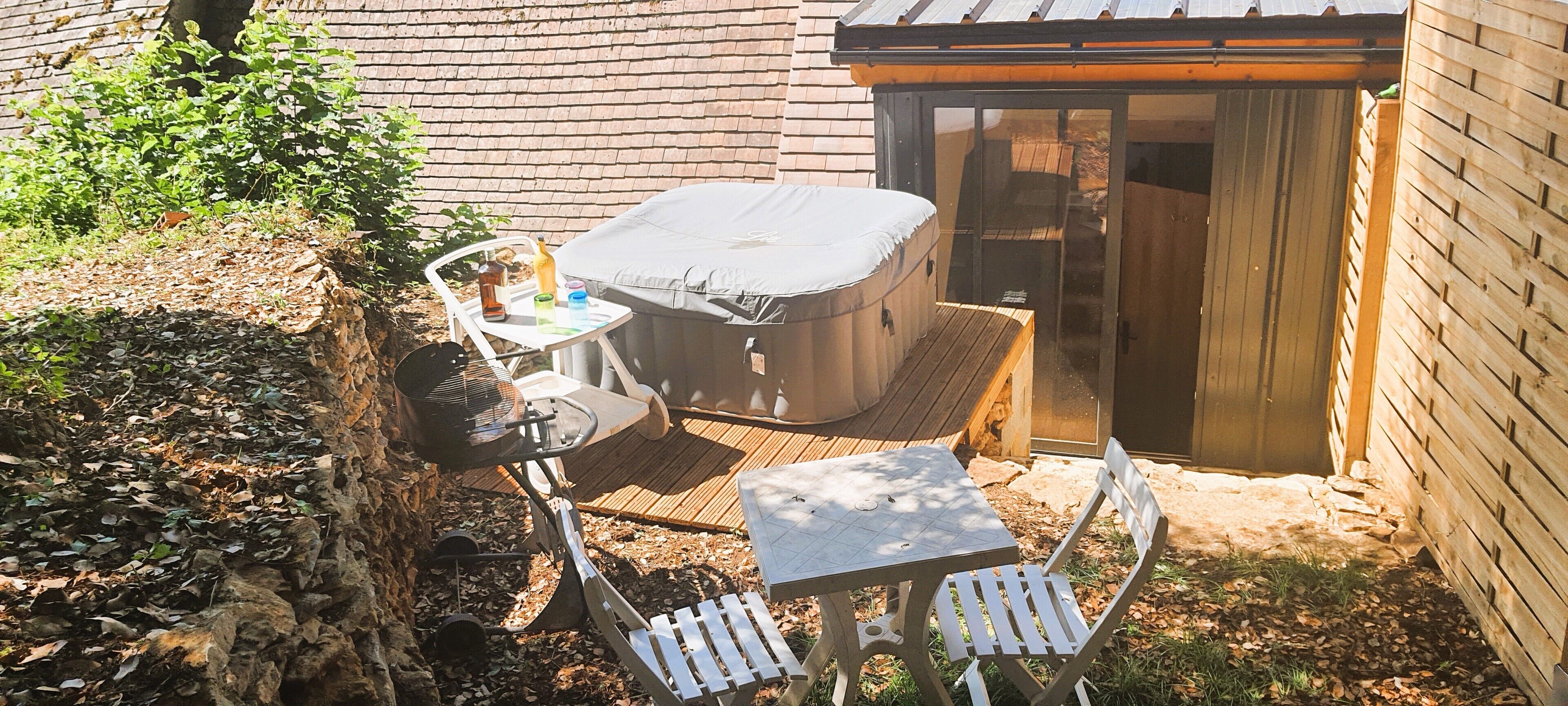 A patio area with a hot tub, a table, and chairs.