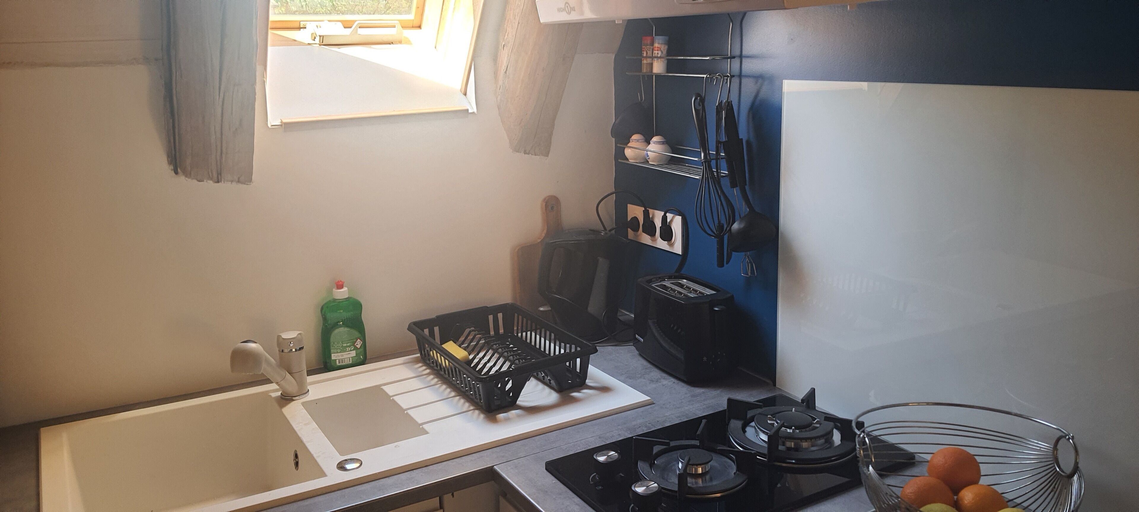 Uma cozinha compacta com fogão a gás, pia e bancada pequena.