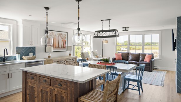 Una cocina amplia con una isla grande, armarios de madera y elegantes lámparas colgantes.
