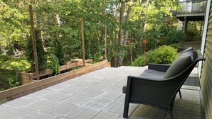 Un patio con una silla de mimbre y una maceta de madera.