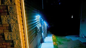 Un camino que lleva a una casa con fachada de ladrillo y valla de metal.