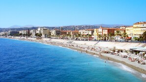 A coastal cityscape with a beach, buildings, and clear blue waters.