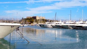A marina with multiple boats docked, a clear sky, and a castle in the background.