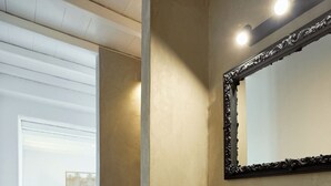 Un baño moderno con un lavabo de piedra, un espejo grande y una bañera blanca al fondo.
