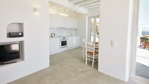 Una cocina moderna con armarios blancos, horno empotrado y zona de comedor con mesa y sillas.