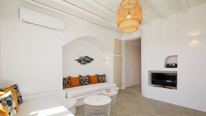 Una sala de estar moderna con un sofá blanco, un televisor montado en la pared y una mesa de centro redonda.