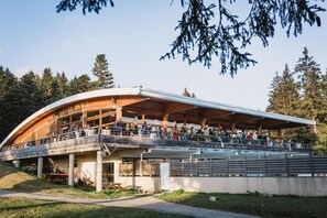 A restaurant with an outdoor seating area, a covered deck, and a view of the surrounding forest. - 70m from ski slopes, fitness, swimming pool, sauna, terrace, balcony, parking, tv, 26-30m² (Chamrousse)