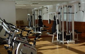 A gym with exercise equipment including treadmills, weight machines, and a pull-up bar.