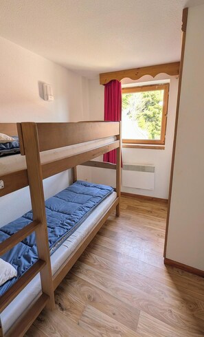 A bunk bed room with a window, wooden flooring, and a red curtain. - 70m from ski slopes, fitness, swimming pool, sauna, terrace, balcony, parking, tv, 25m², Chamrousse (Chamrousse)