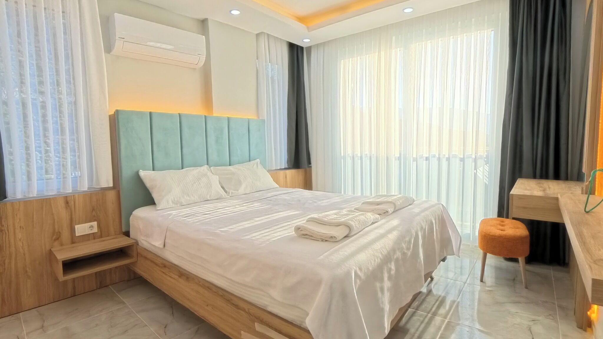 A modern hotel room with a bed, a desk, and a chair.