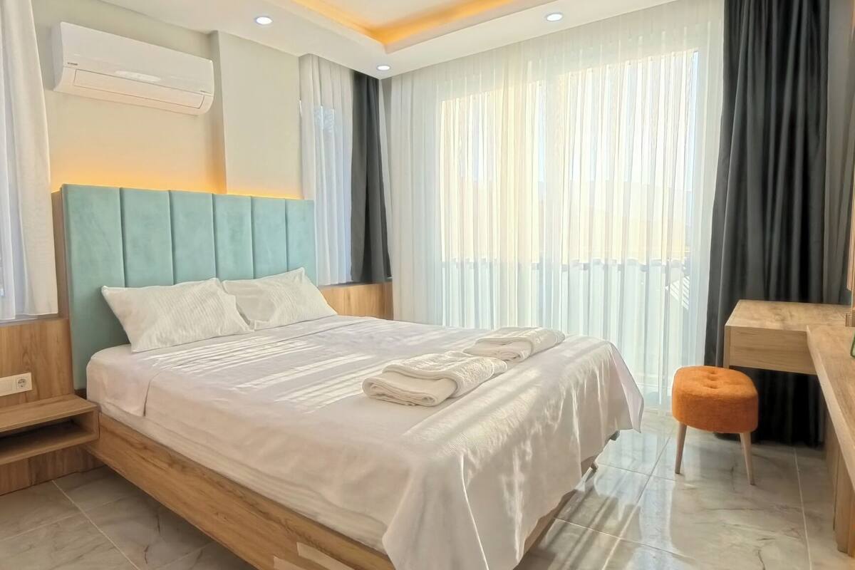 A modern hotel room with a bed, a desk, and a chair.