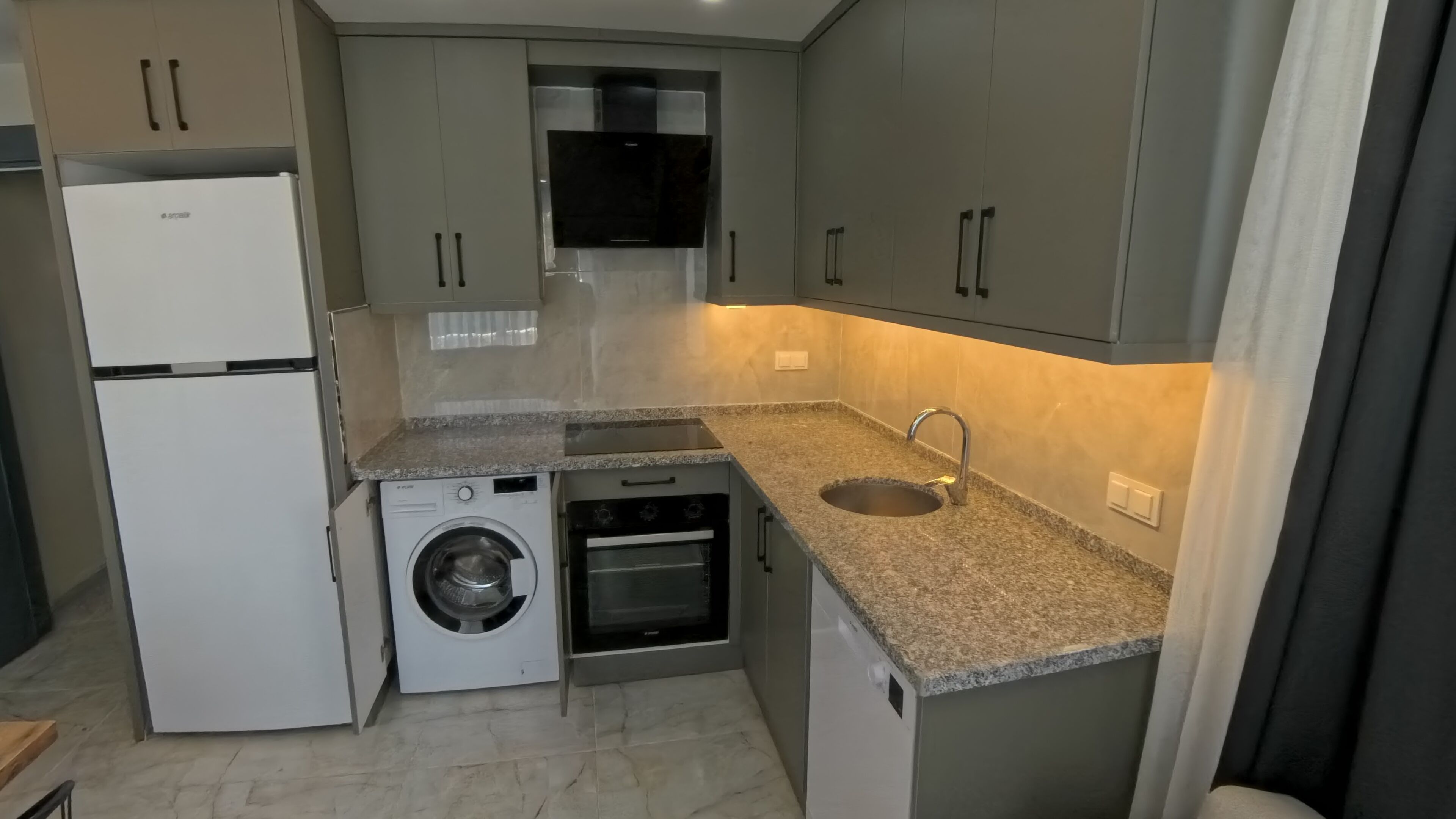 Una cocina compacta equipada con lavadora, horno y microondas integrados.