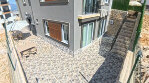Un edificio moderno con un patio piastrellato, arredi da esterno e una scalinata in pietra.