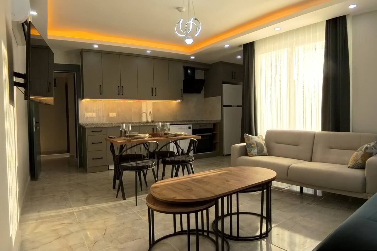 A modern living room with a sofa, a coffee table, and a dining area with chairs and a table.