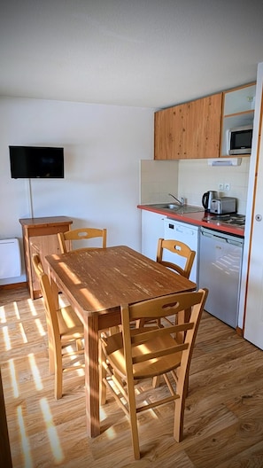 A compact kitchen with wooden cabinets, a microwave, a toaster, and a sink.