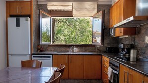 A kitchen with wooden cabinets, a built-in oven, a microwave, and a window overlooking greenery. - L' Ametller - House Alt Empordà / Costa Brava, barbecue, volleyball (Ordis)