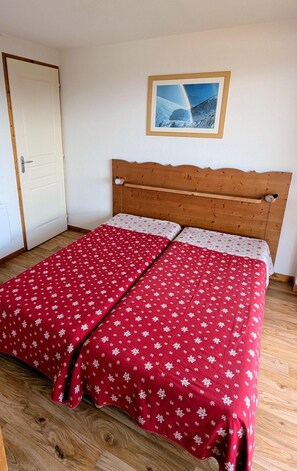 A single bed with a wooden headboard in a room with a white door and a framed picture on the wall.