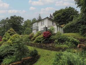 Een huis met twee verdiepingen, een stenen muur en een tuin.