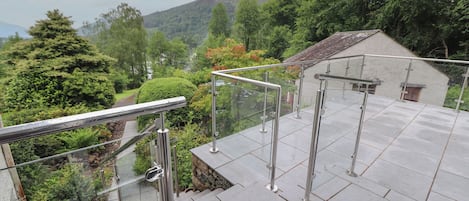 Una escalera con barandas de metal que conduce a una terraza con vistas a una ladera boscosa.
