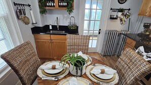 A dining area with a round wooden table set for four, surrounded by wicker chairs. - Dazzling Oceanview-4 Train Stop Logan Airport (Revere)