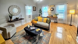 A living room with a sofa, armchair, coffee table, and a lamp. - Dazzling Oceanview-4 Train Stop Logan Airport (Revere)