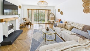 Un salon moderne avec une cheminée, un canapé, une table basse et une grande fenêtre équipée de stores.
