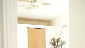 A bedroom with a bed, a wooden door, a ceiling fan, and a plant on a shelf. - Charming 3BR 2BA Home – Walk to Downtown St. Albans, Near Lake Champlain (Saint Albans City)