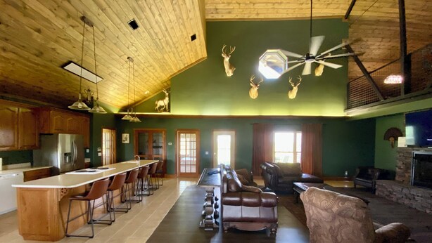 A spacious living area with a long dining table, leather sofas, and a fireplace.