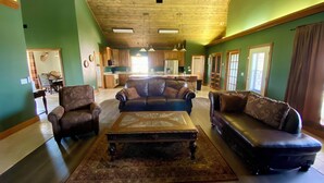 A spacious living room with a large sofa, a coffee table, and a dining area in the background.